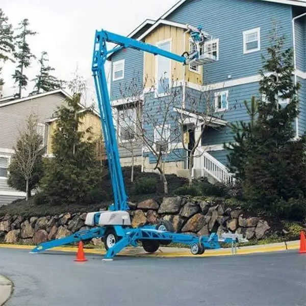 Blue trailer-mounted boom lift for house exterior painting and repair