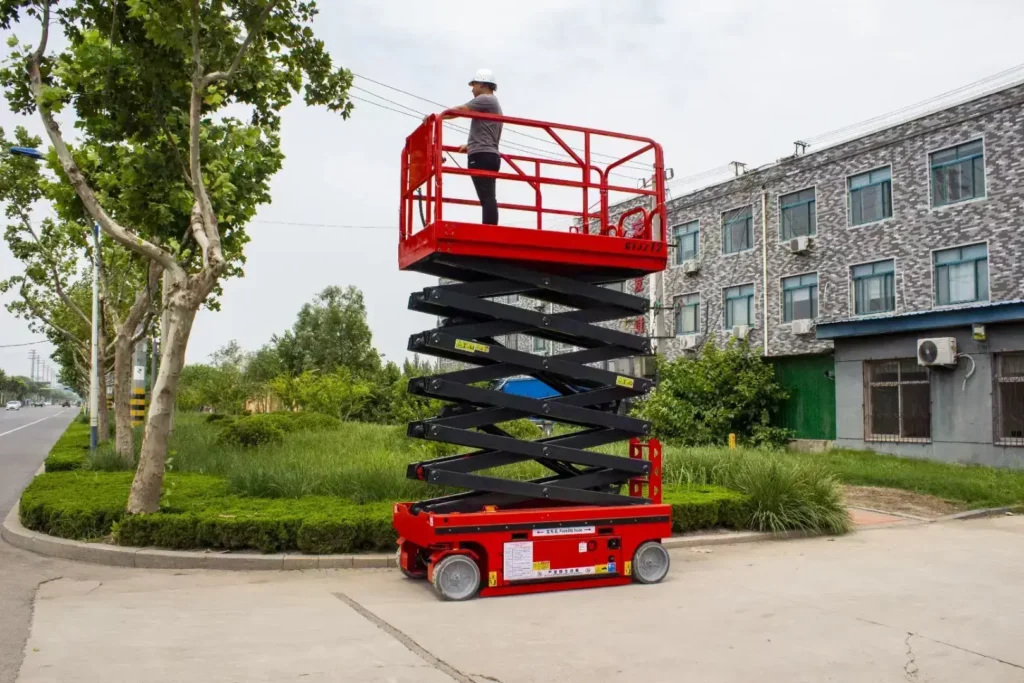 Red electric scissor lift with operator, showcasing standard scissor lift load capacity for indoor maintenance