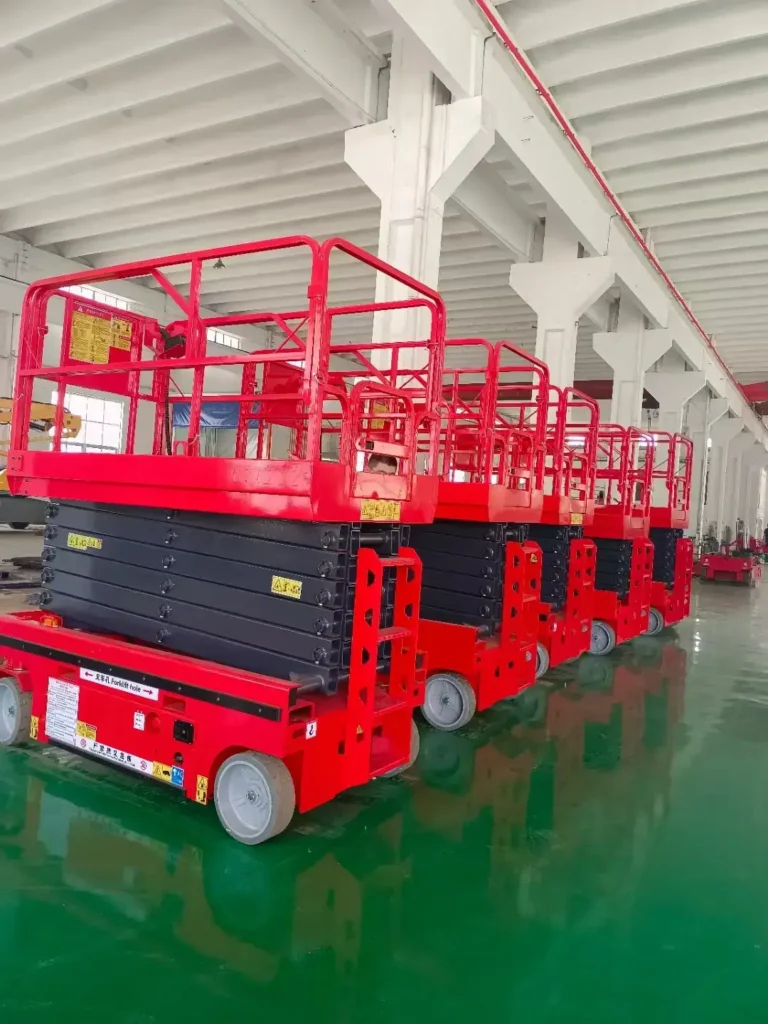 Red electric warehouse scissor lift parked inside a factory workshop